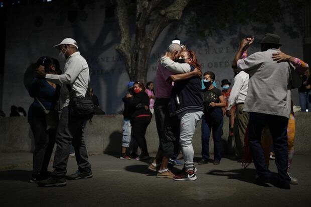 Varias personas se abrazan en una calle, de noche